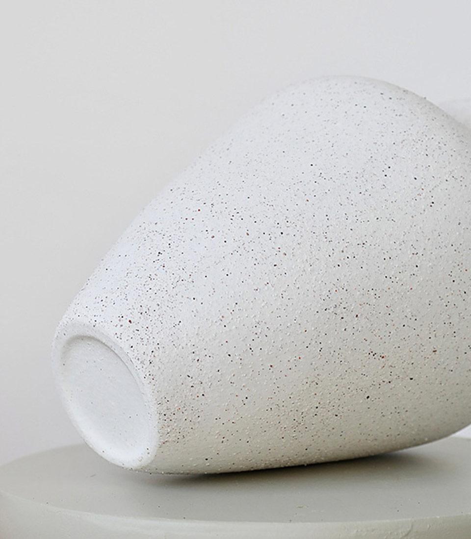 Close-up of the speckled underside of a minimalist white vase.