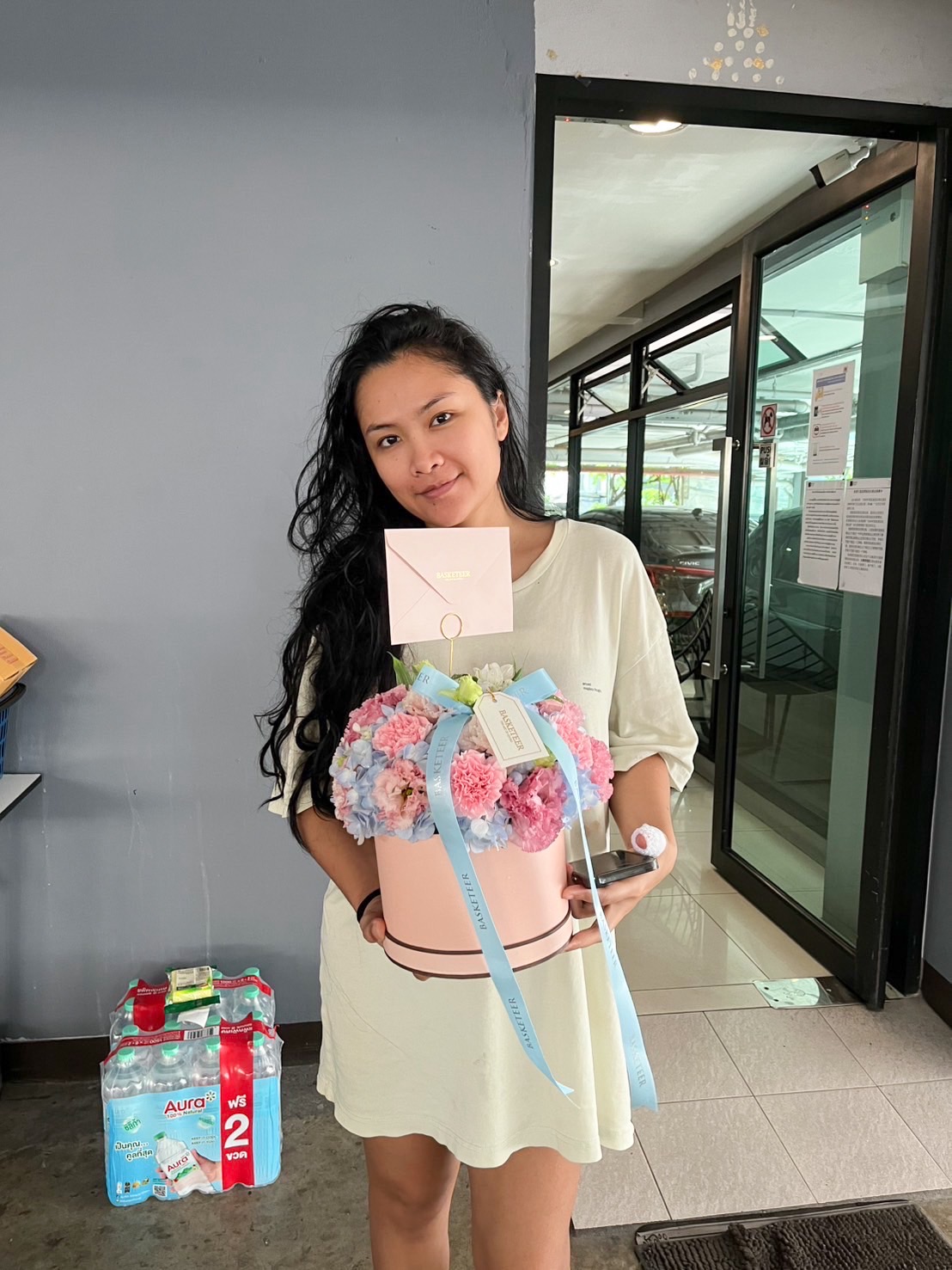 Pastel pink round flower box with hydrangeas, carnations, and fresh blooms in soft pink and blue tones, tied with a blue ribbon