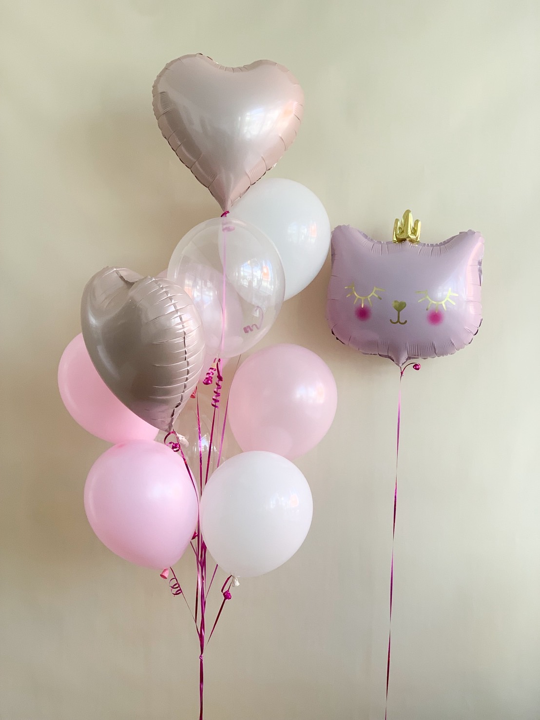 Pink kitty foil balloon with crown and heart-shaped and round pink white helium balloons for birthday and celebration decoration.