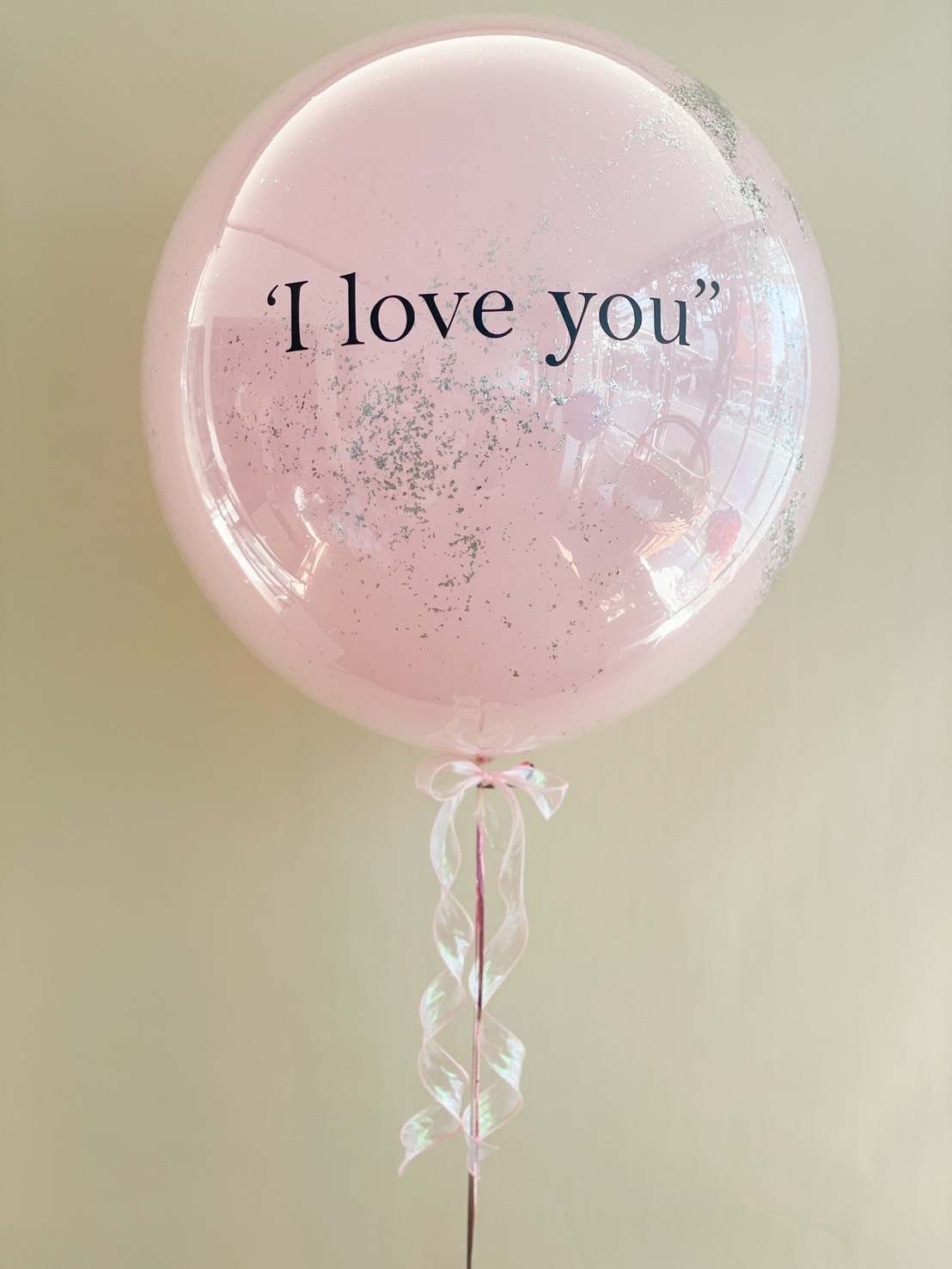 Elegant pink bubble balloon with ‘I Love You’ text, adorned with a glitter effect and ribbon tail—a perfect romantic gift for any occasion.