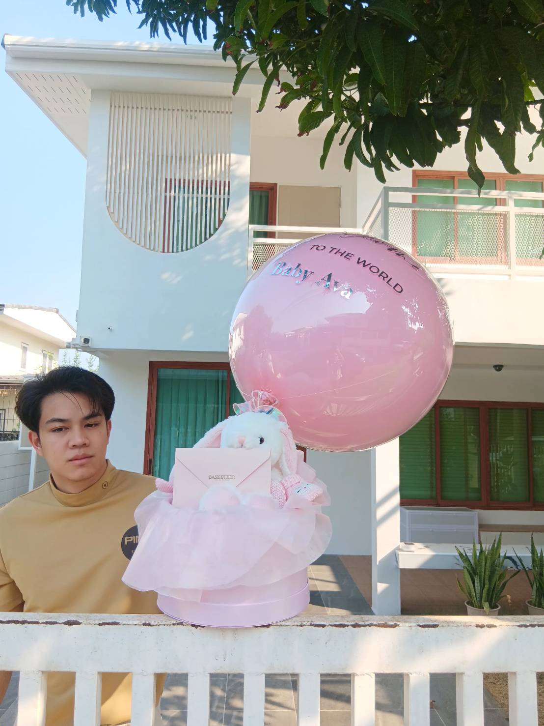 A charming baby gift set with a customized pink balloon, a soft plush bunny, and an elegant hat box with delicate fabric wrapping—perfect for celebrating a newborn baby’s arrival.