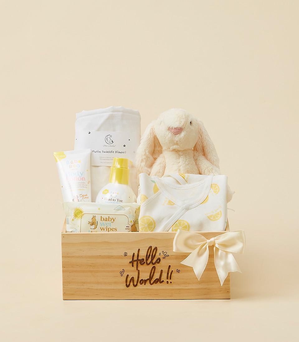 A charming baby shower gift containing a bunny, baby clothes, and accessories, presented in a wooden crate.