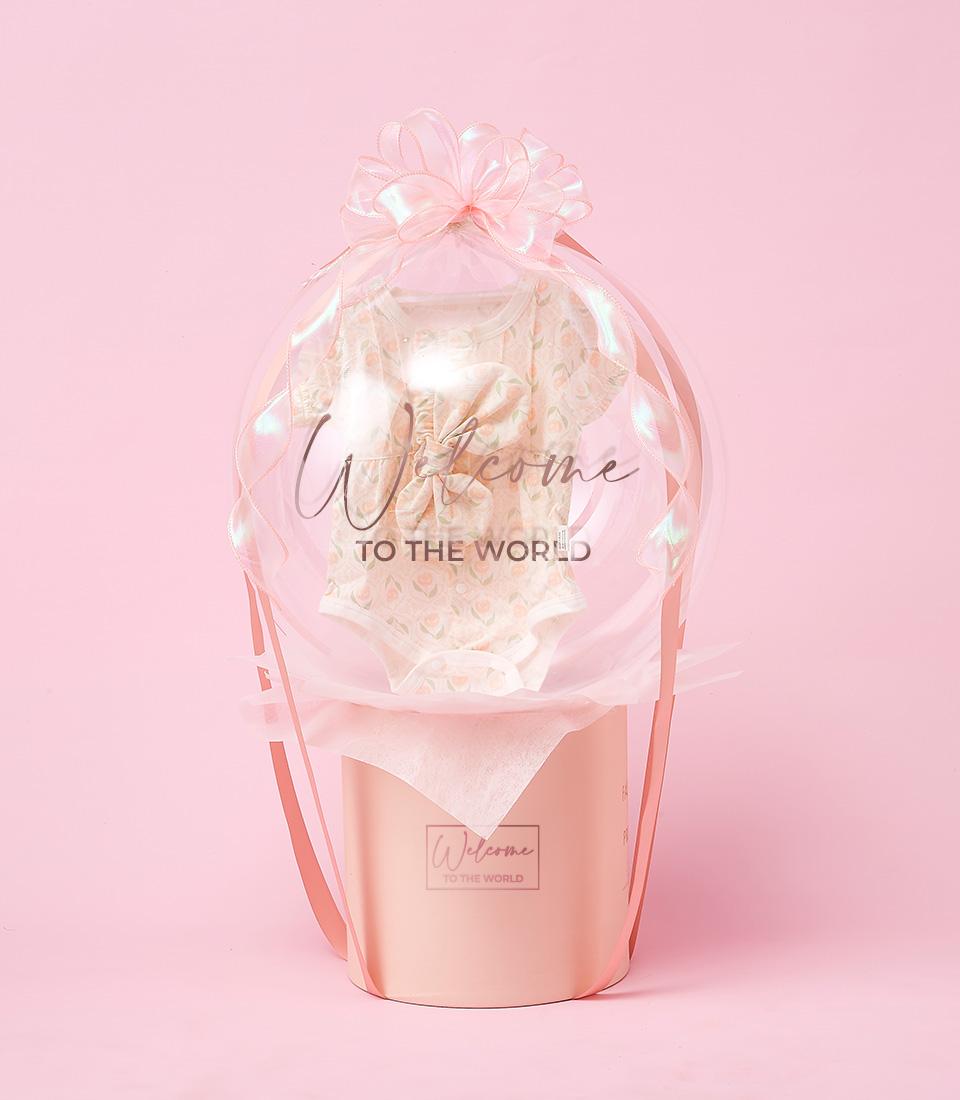 A gift basket wrapped in transparent cellophane, topped with a pink bow and the text 