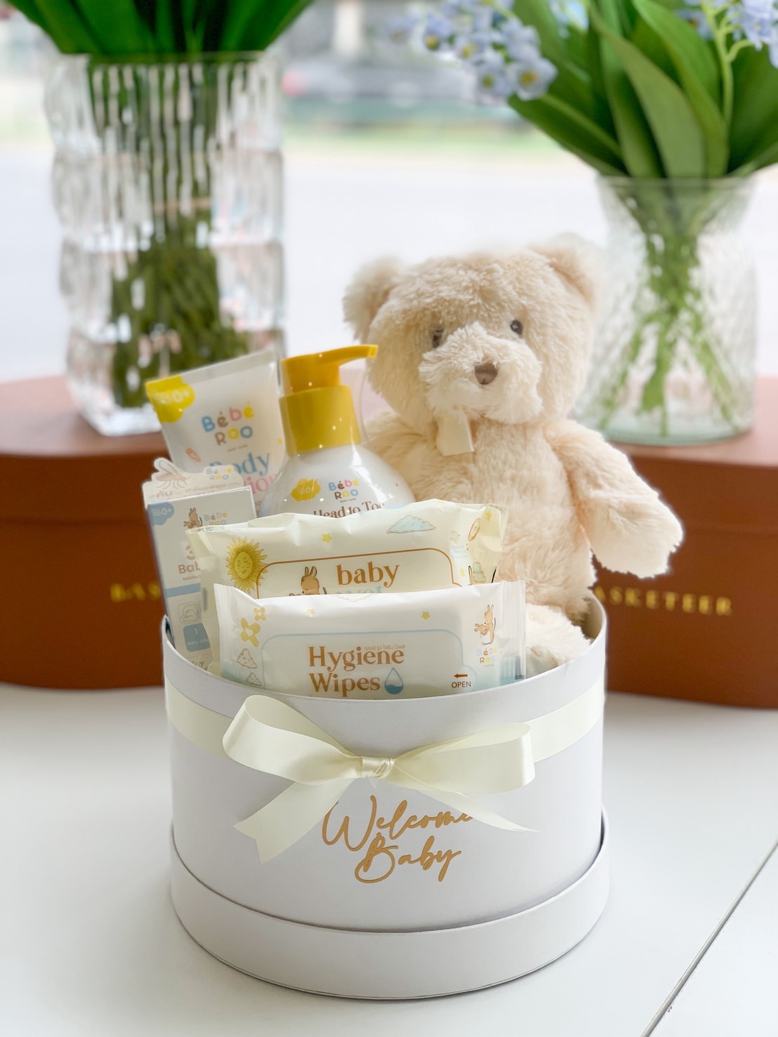 Round white baby gift box with wipes, baby lotion, head-to-toe wash, and a plush teddy bear.