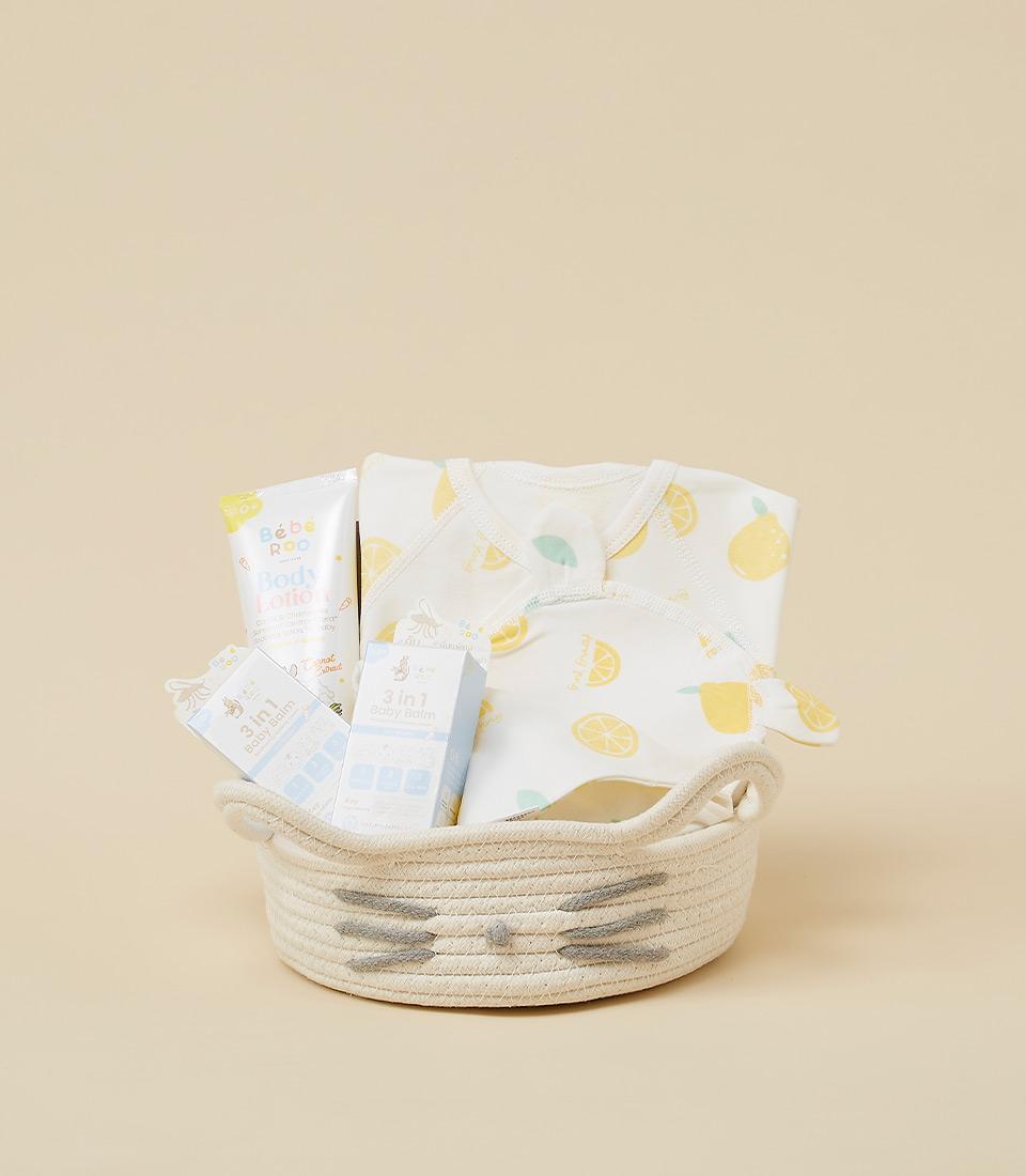 A woven basket filled with baby essentials, including a bodysuit, bib, lotion, and other products.