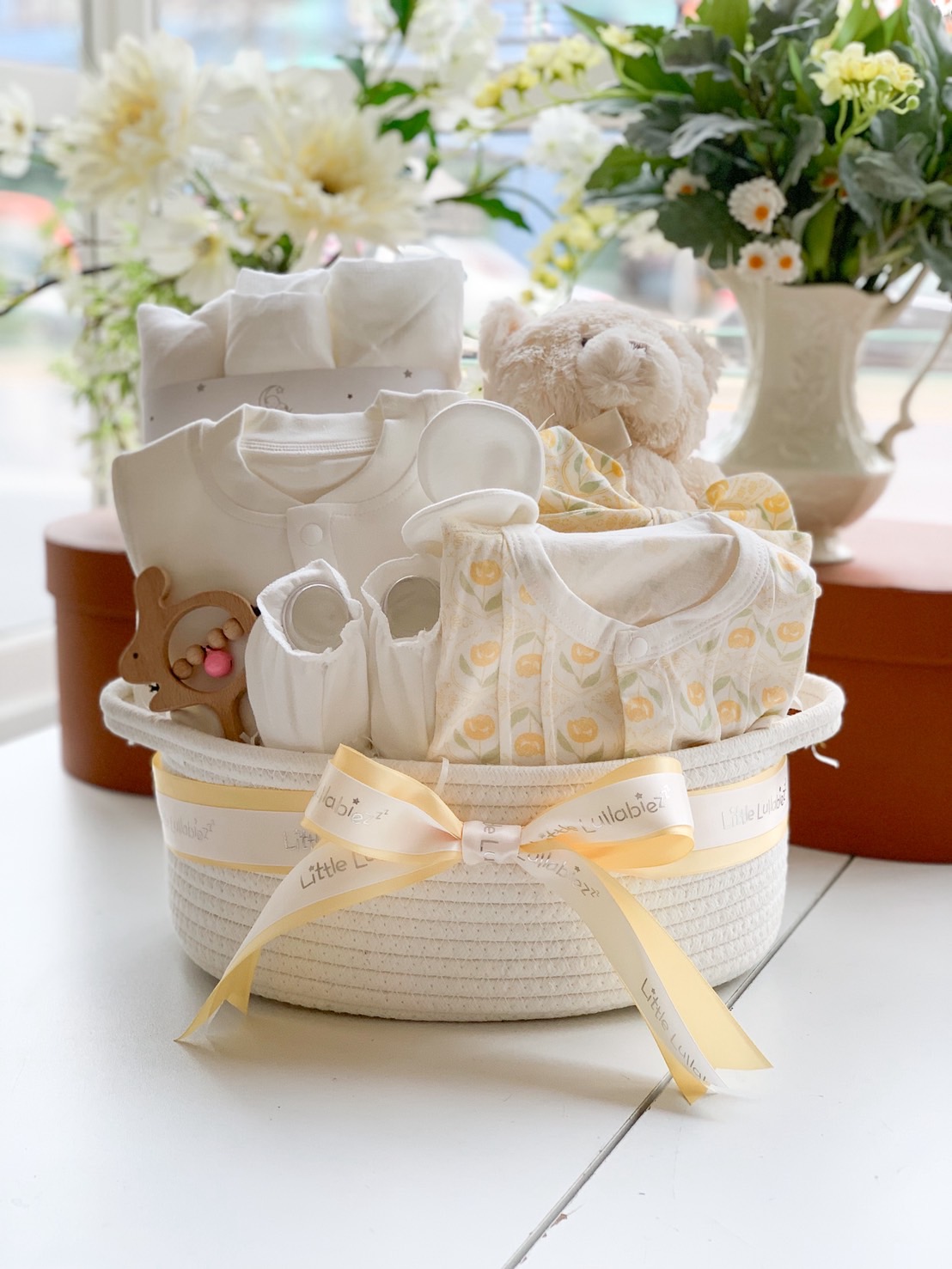 Premium yellow baby gift basket with teddy bear, baby clothes, wooden toy, and accessories. Perfect newborn or baby shower gift.