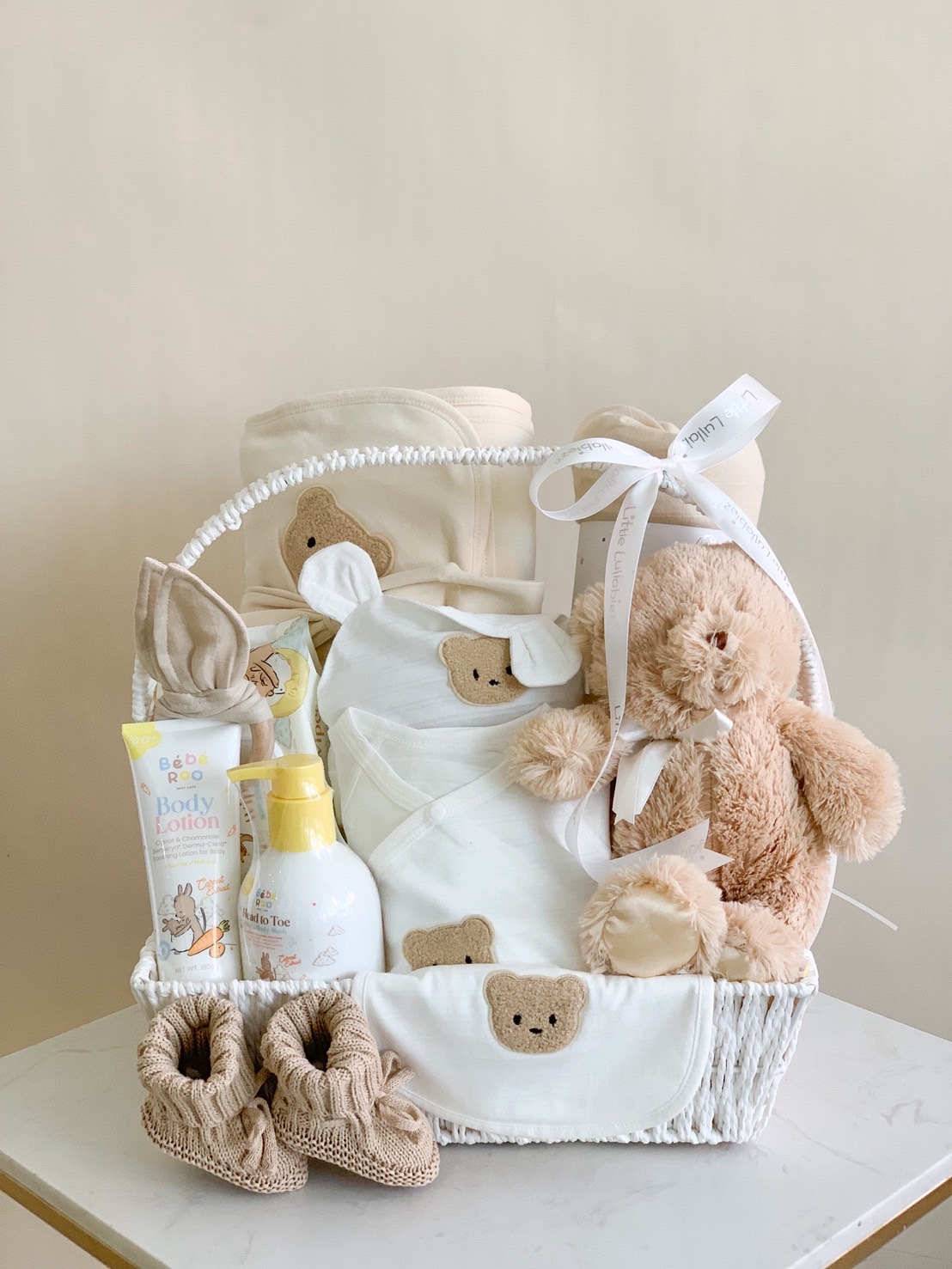 Luxury neutral bear baby gift basket with baby clothes, knitted shoes, lotion, and plush teddy. Perfect newborn hamper gift.