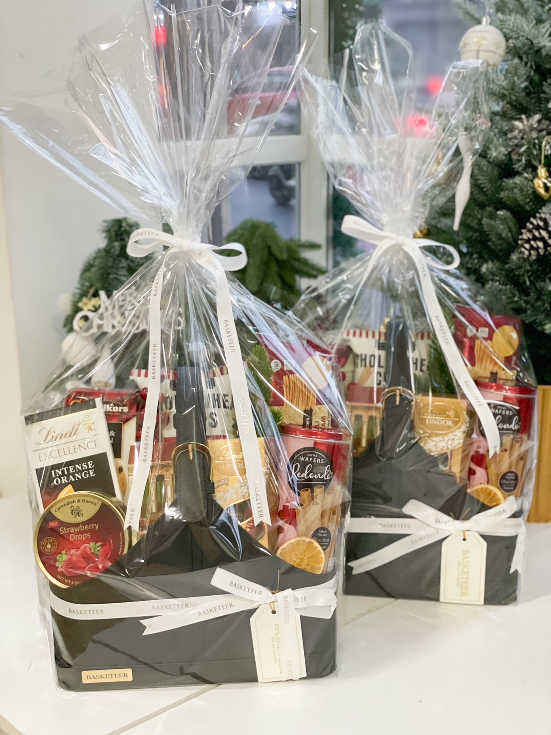 Elegant black basket filled with premium chocolates, cookies, and gourmet treats by Basketeer.