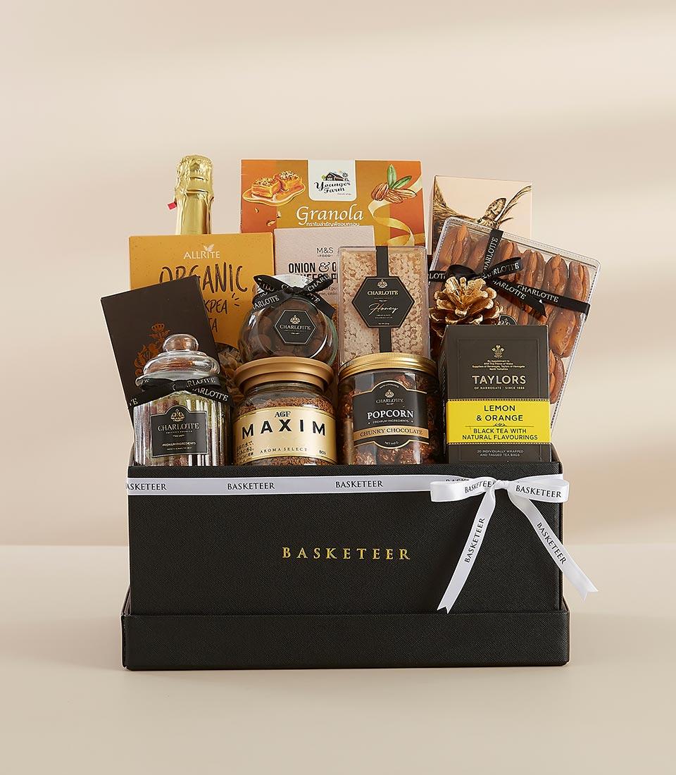 Deluxe gourmet gift hamper featuring organic chickpea pasta, granola, chocolates, popcorn, black tea, and Carbonated Red Grape Juice.