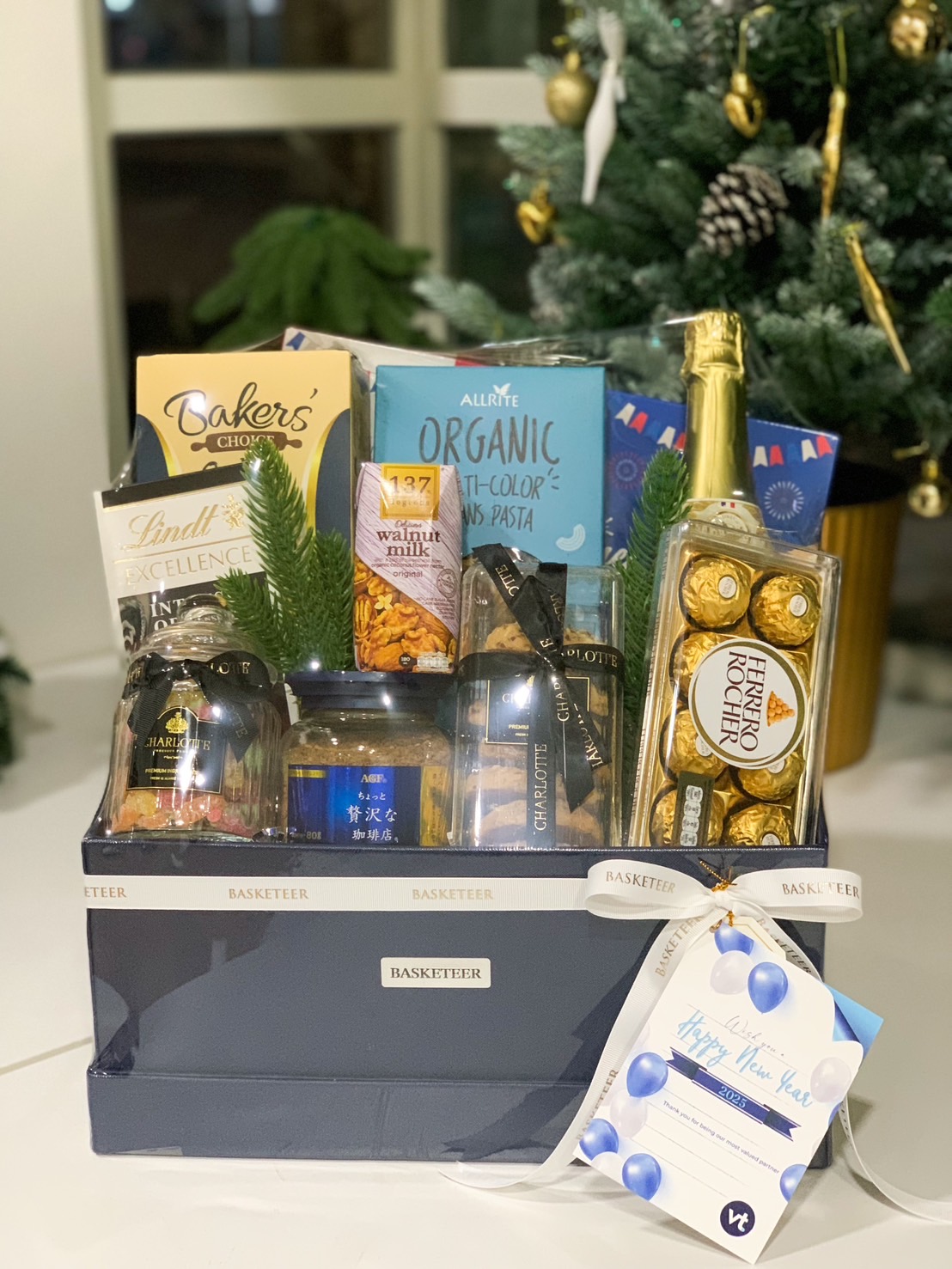 Luxurious New Year gift basket in a navy blue box, filled with premium chocolates, cookies, organic pasta, and a sparkling beverage.