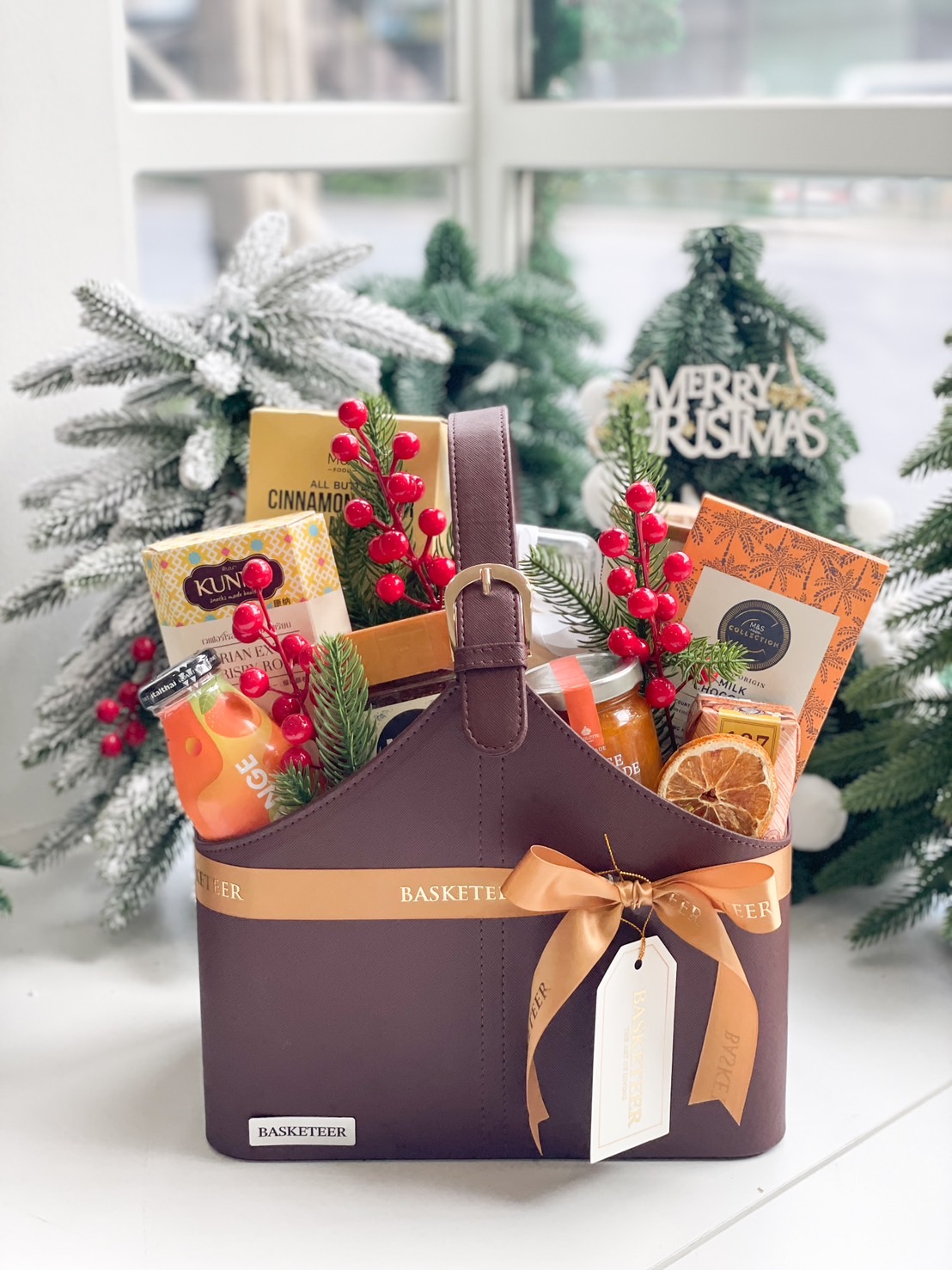 A brown leather basket filled with a variety of gourmet food items.