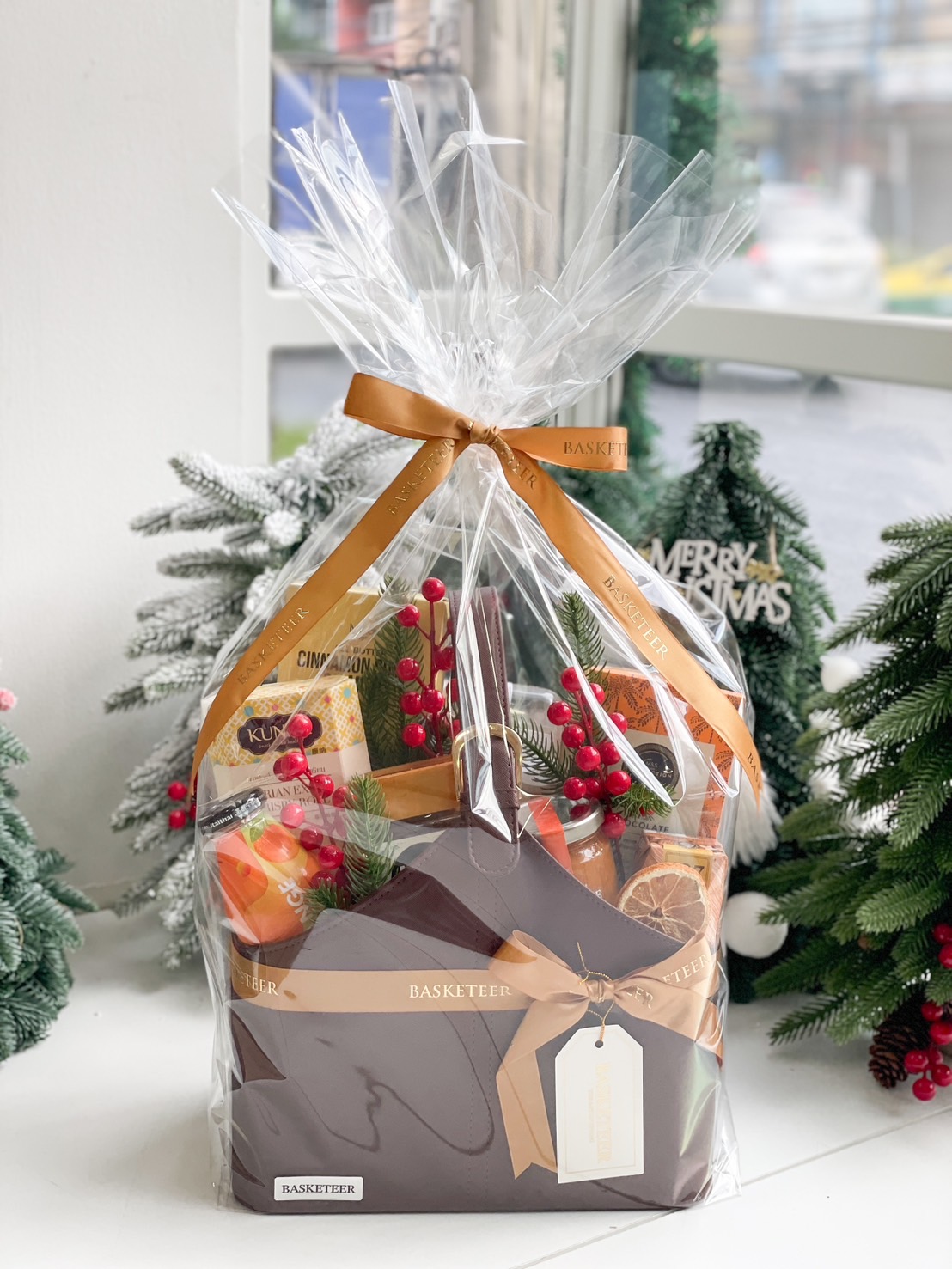 A brown leather basket filled with a variety of gourmet food items.