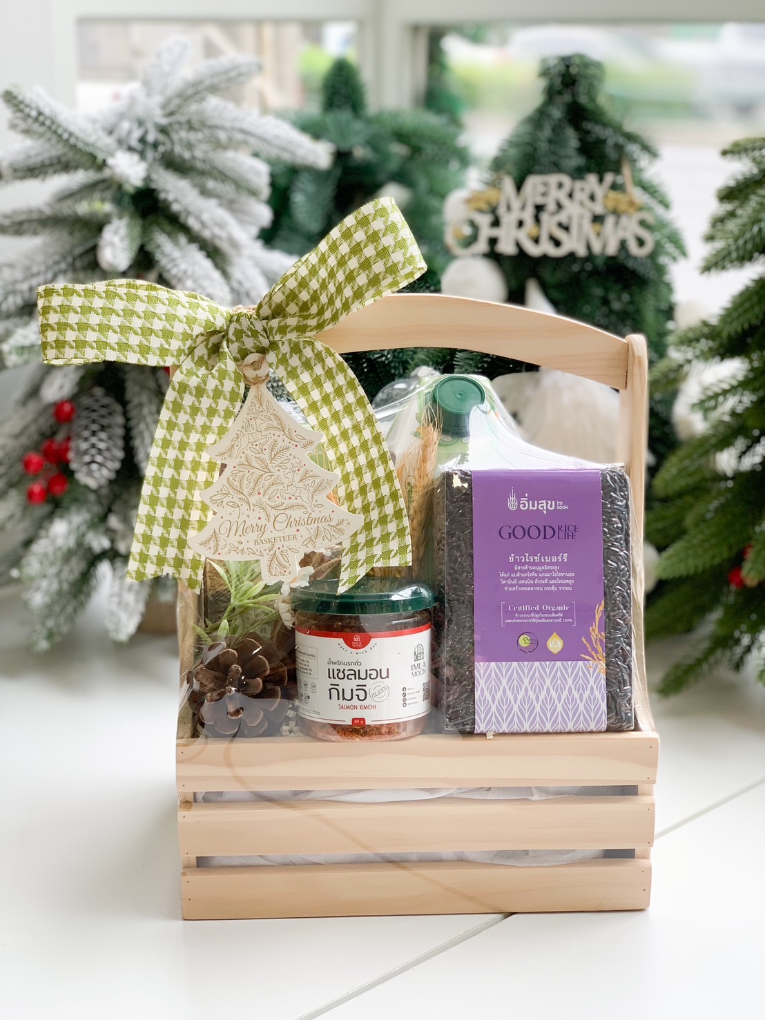 Wooden gift basket with organic rice, herbal drinks, and Thai chili paste tied with a green bow.
