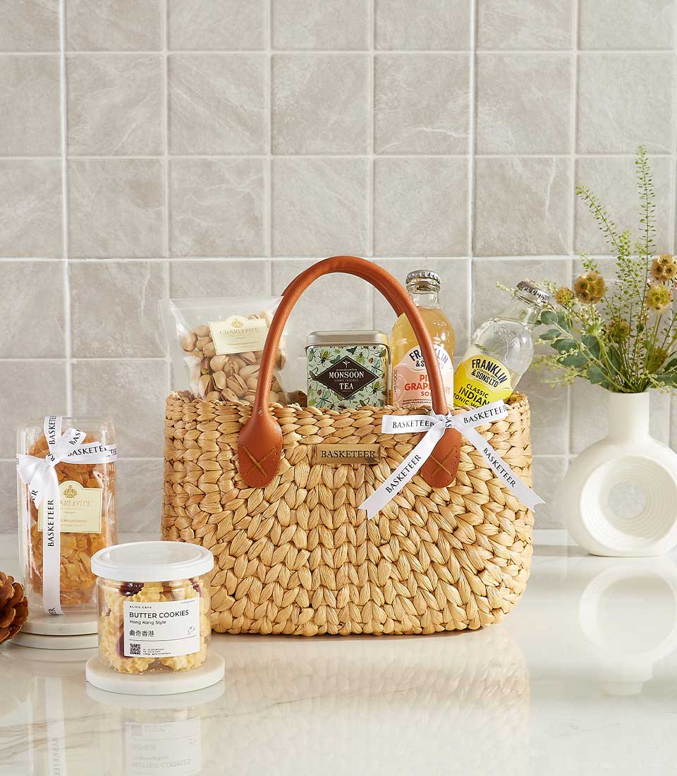 Elegant woven tote gift basket with butter cookies, tea, and beverages.