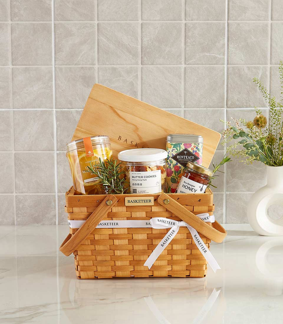 Classic picnic gift basket with butter cookies, honey, orange marmalade, premium tea, and a wooden board.