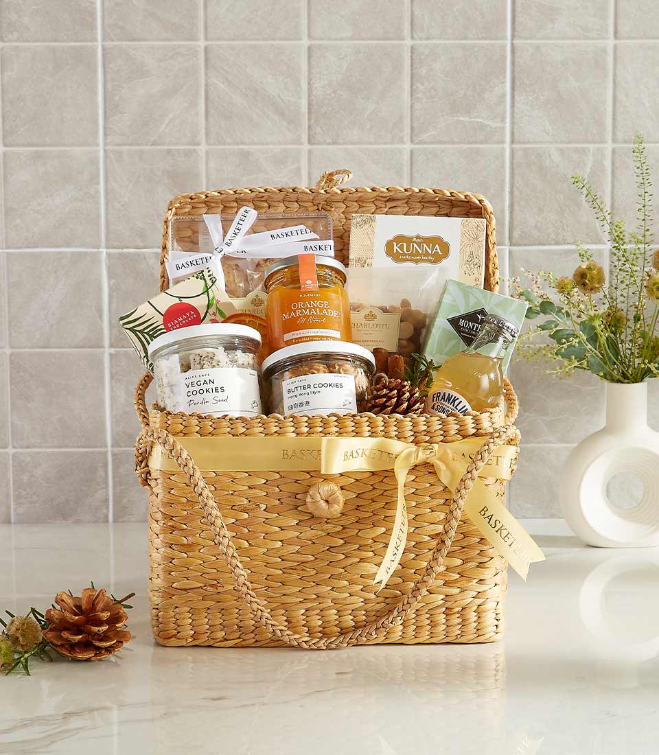 Golden gift basket with orange marmalade, vegan cookies, butter cookies, premium tea, and other gourmet items.