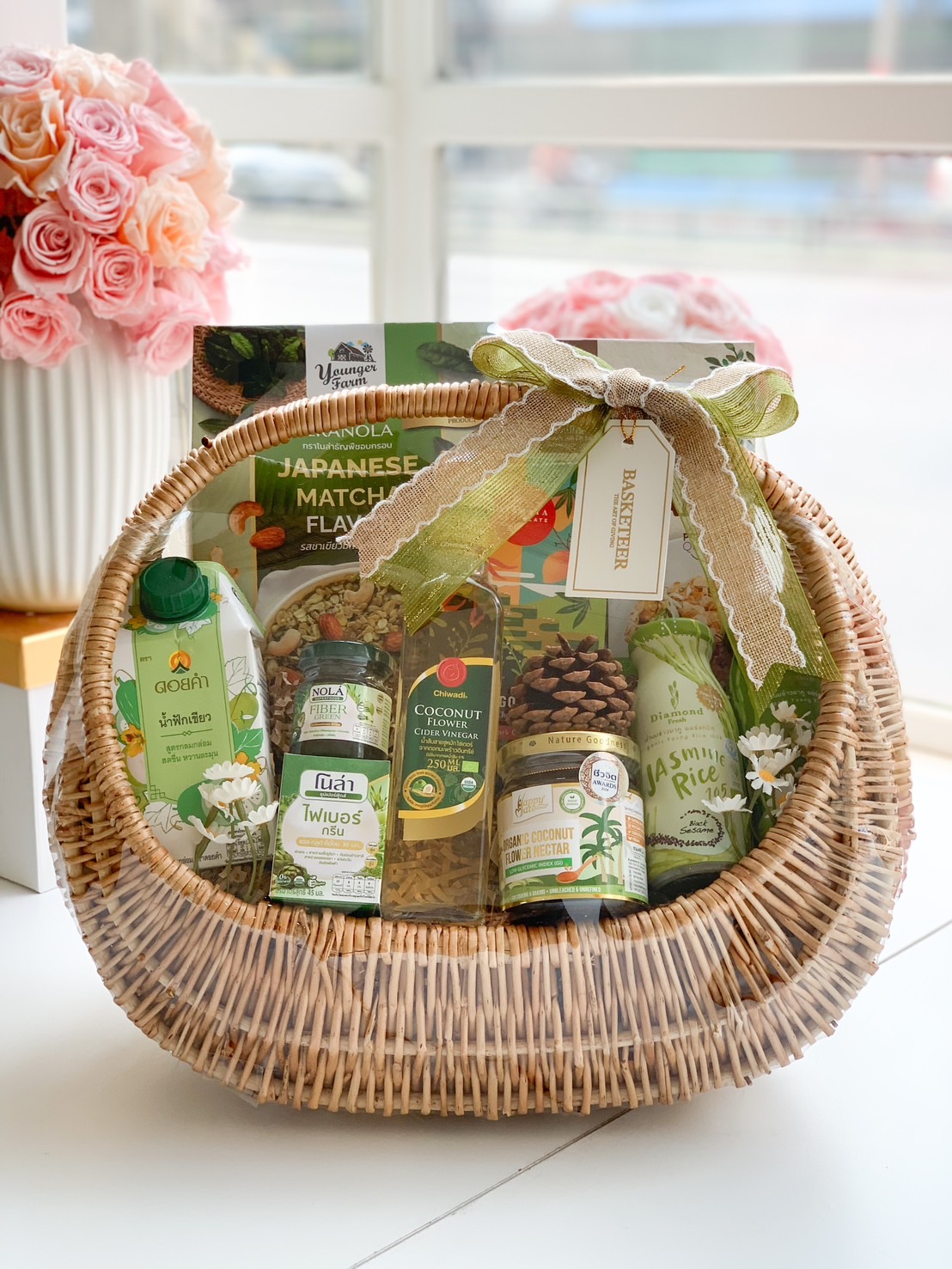 A beautifully arranged healthy gift basket filled with organic snacks, herbal drinks, and wellness essentials, wrapped in a natural wicker basket with a green ribbon.