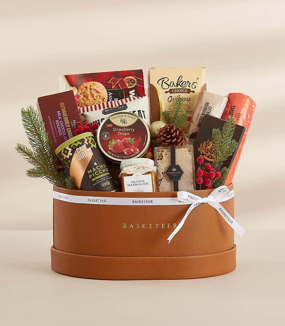 A round gift box filled with a variety of gourmet treats, including chocolates, snacks, and a bottle of orange marmalade.