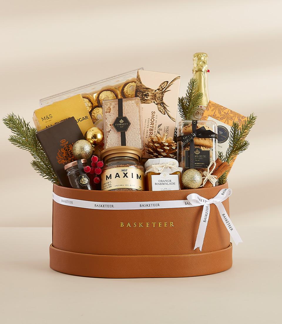 A round gift box filled with a variety of gourmet treats, including chocolates, snacks, and a bottle of sparkling grape juice