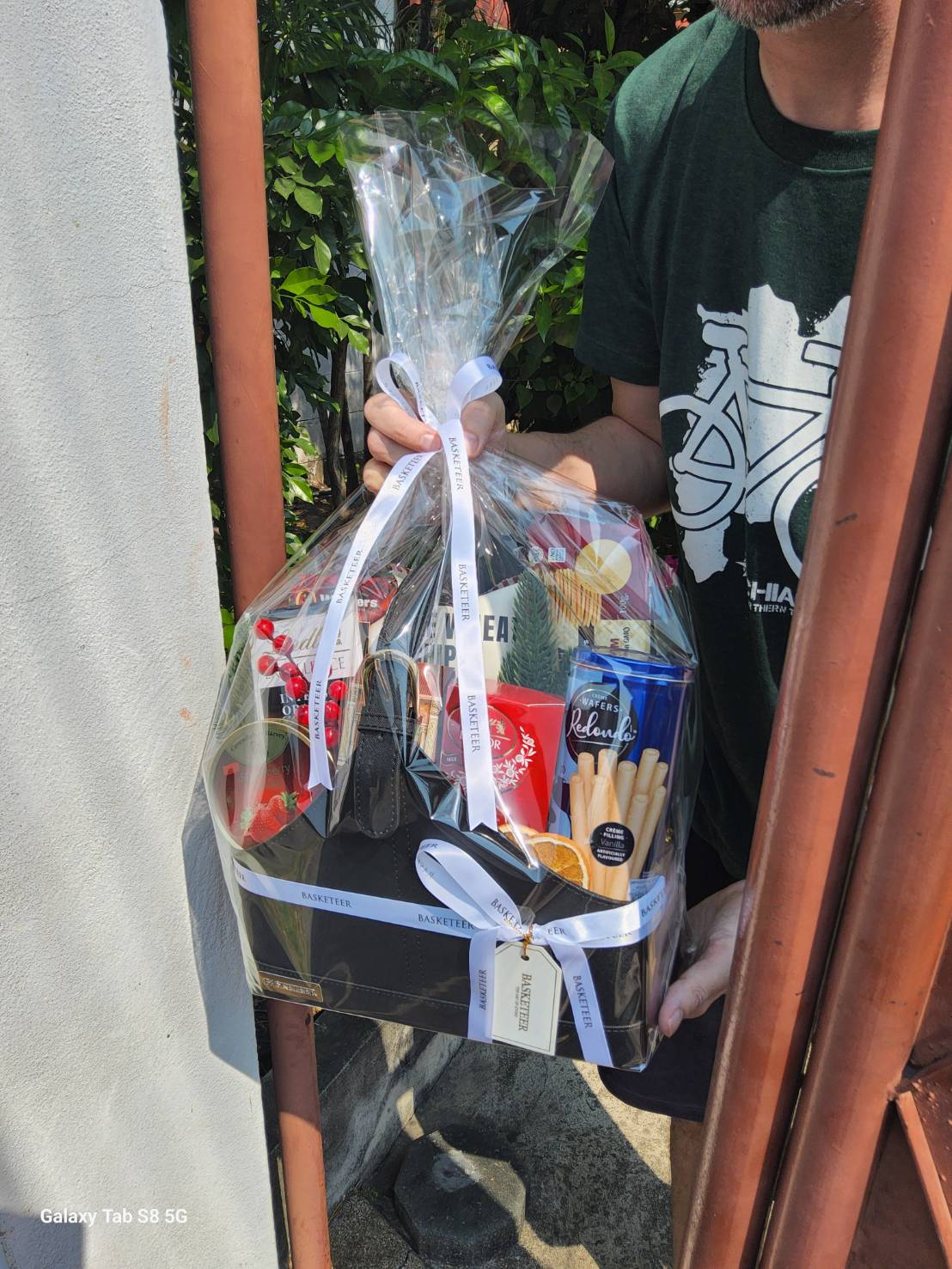 A beautifully wrapped gourmet gift basket featuring a selection of premium chocolates, wafers, biscuits, and sweet treats, elegantly presented with a satin ribbon.