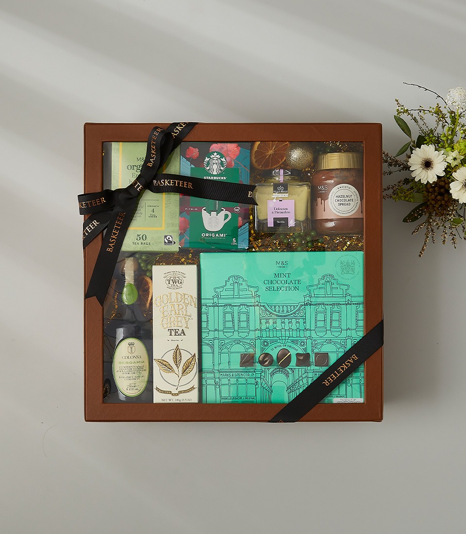 Elegant gift hamper featuring TWG Earl Grey tea, Starbucks Origami coffee, mint chocolate selection, hazelnut spread, and gourmet treats.