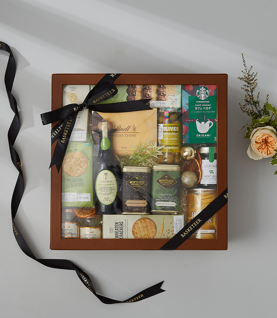 Deluxe gift box with Swiss chocolates, tea, honey lemon, crackers, olives, and gourmet snacks.