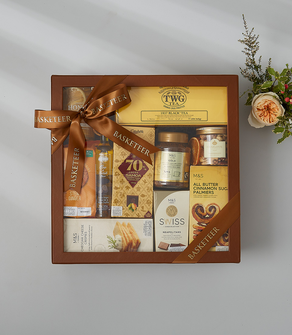Golden gift box with TWG tea, honey lemon, chocolates, cookies, and cinnamon sugar treats.