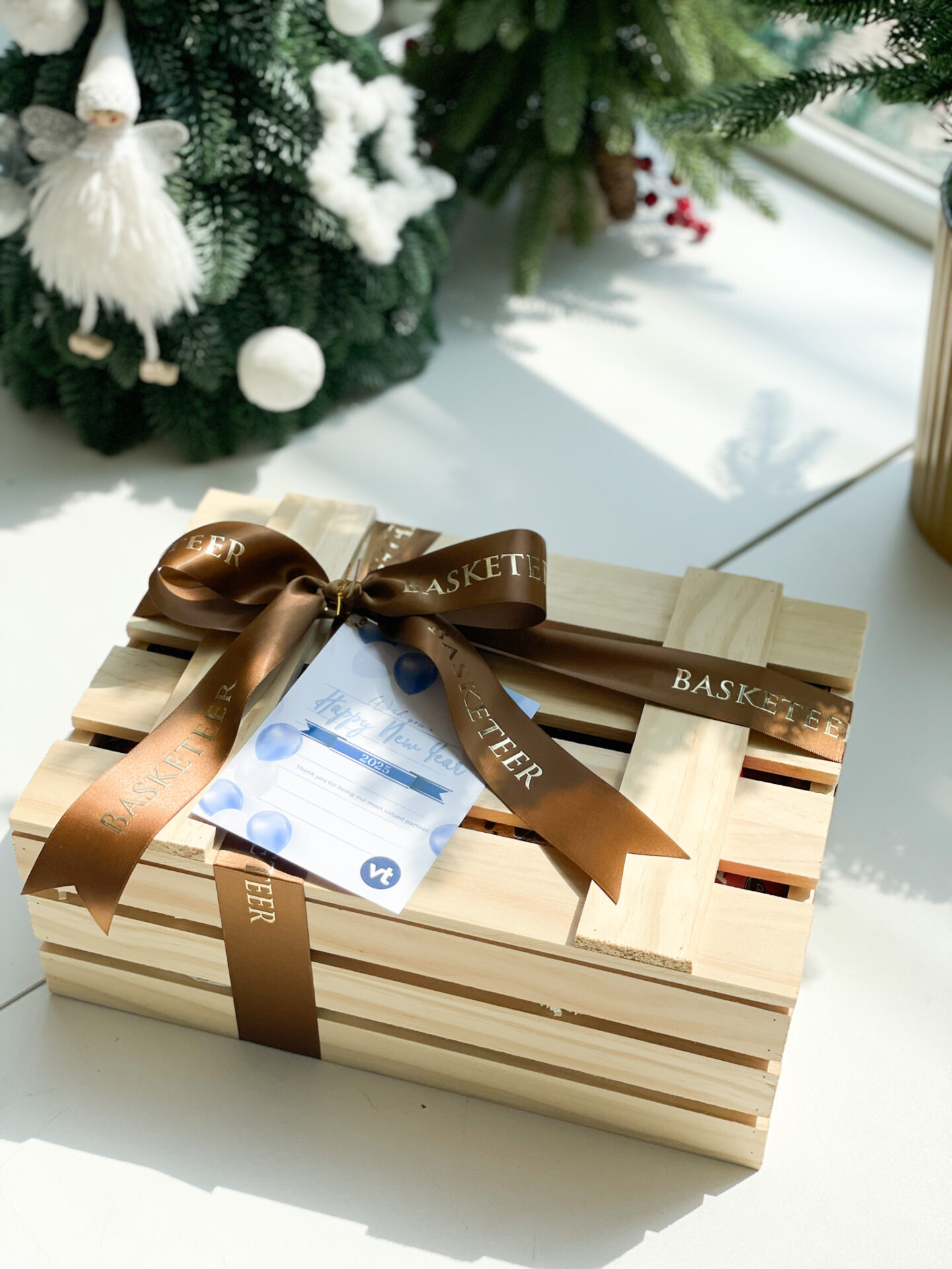Wooden gift box wrapped with a luxurious brown ribbon from Basketeer, featuring a festive card for holiday celebrations.