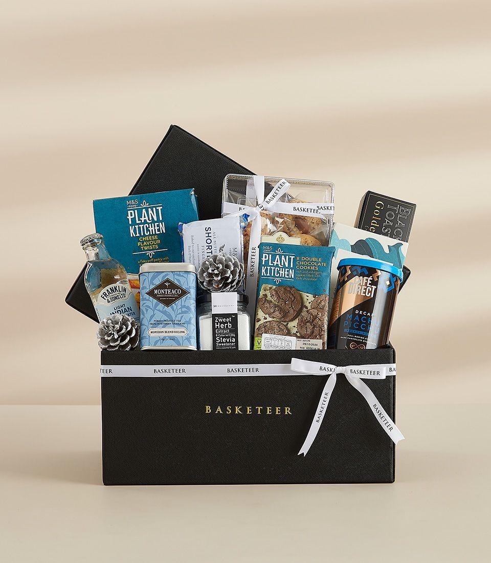 Black gift box filled with premium treats including crackers, English breakfast tea, and Dutch cocoa, tied with a white ribbon.