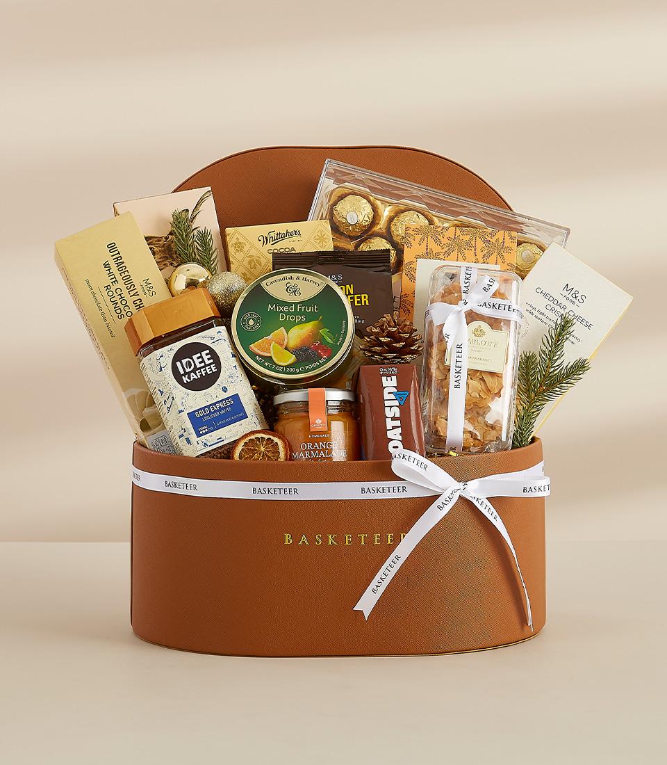 A brown gift basket filled with a variety of gourmet food items, including chocolates, biscuits, coffee, and fruit.