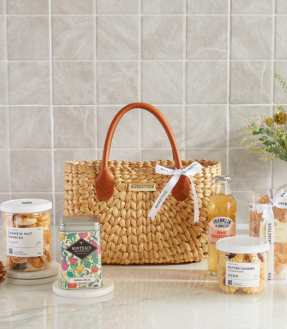 Handwoven tote gift basket with cookies, tea, and pink grapefruit soda.