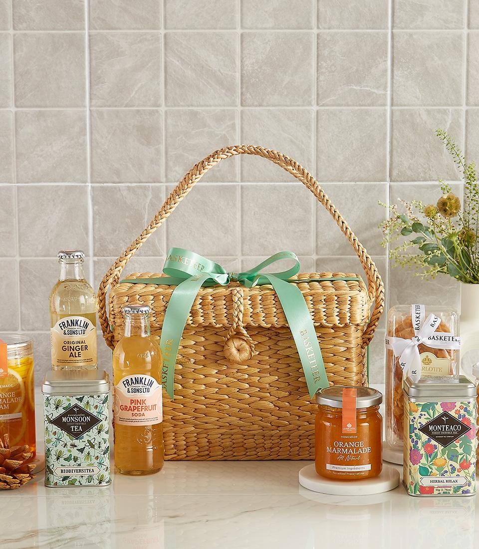 Gourmet picnic basket with herbal teas, ginger ale, pink grapefruit soda, and orange marmalade.