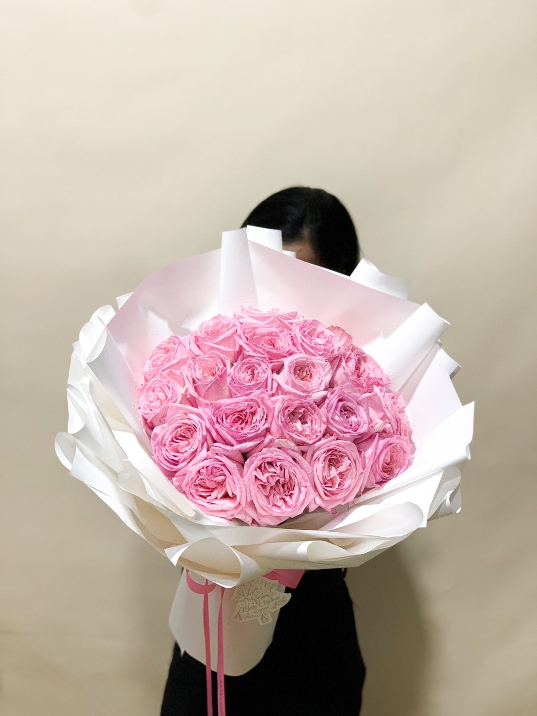 Bouquet of pink roses wrapped in white paper, ideal for romantic occasions.