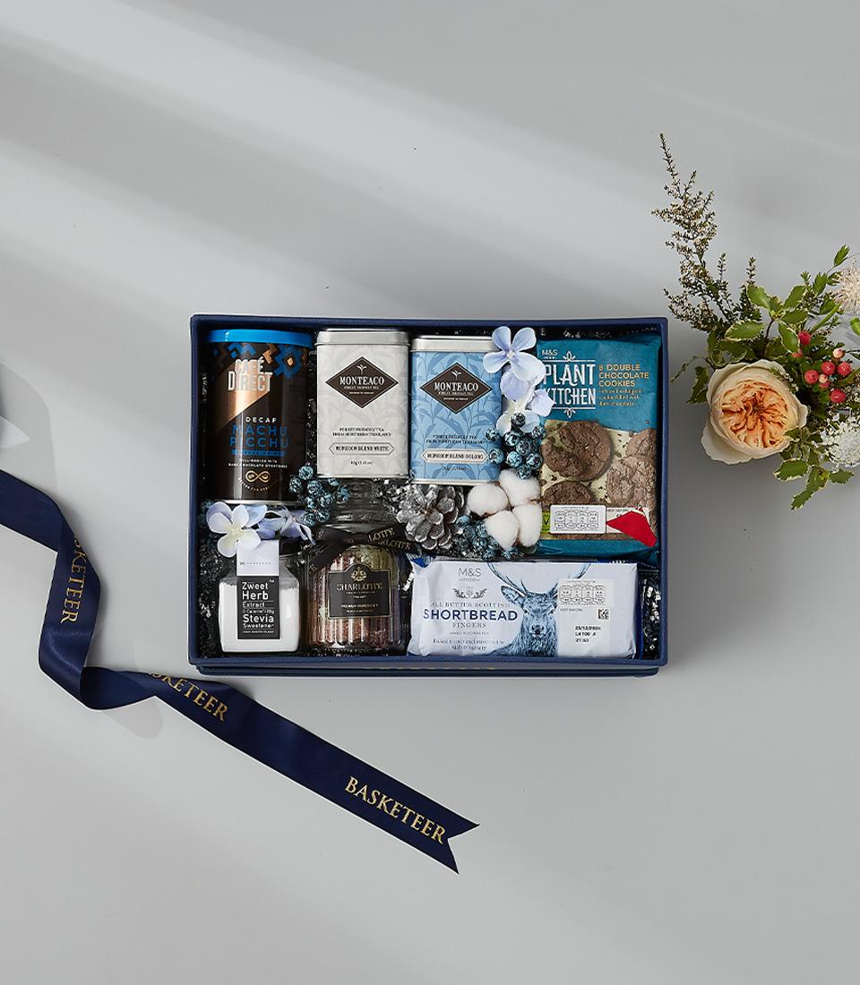 Winter-themed gift hamper with coffee, cookies, stevia, and shortbread in an elegant blue box.