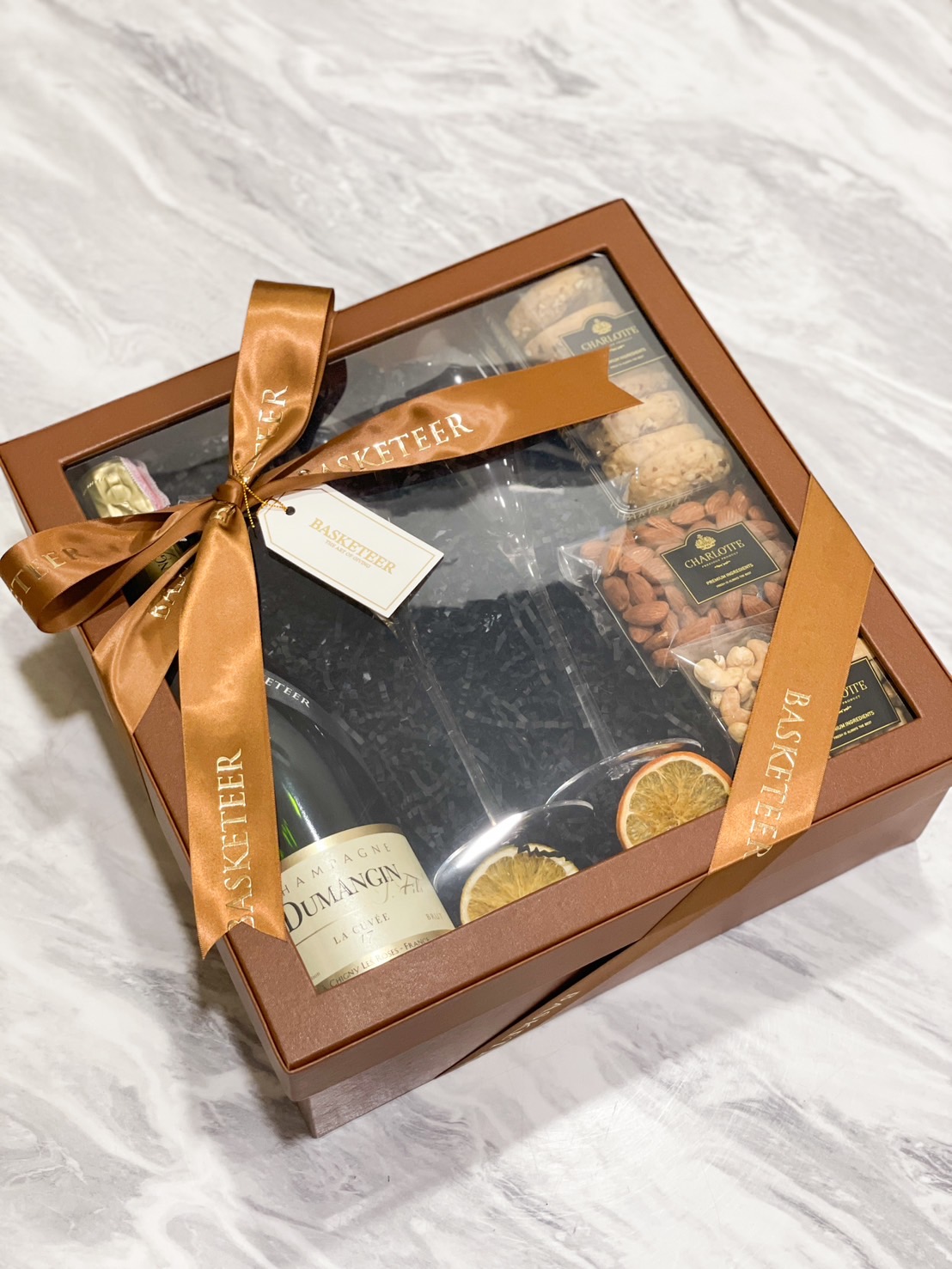 Elegant gift box with a premium bottle, assorted cookies, almonds, and dried citrus by Basketeer.