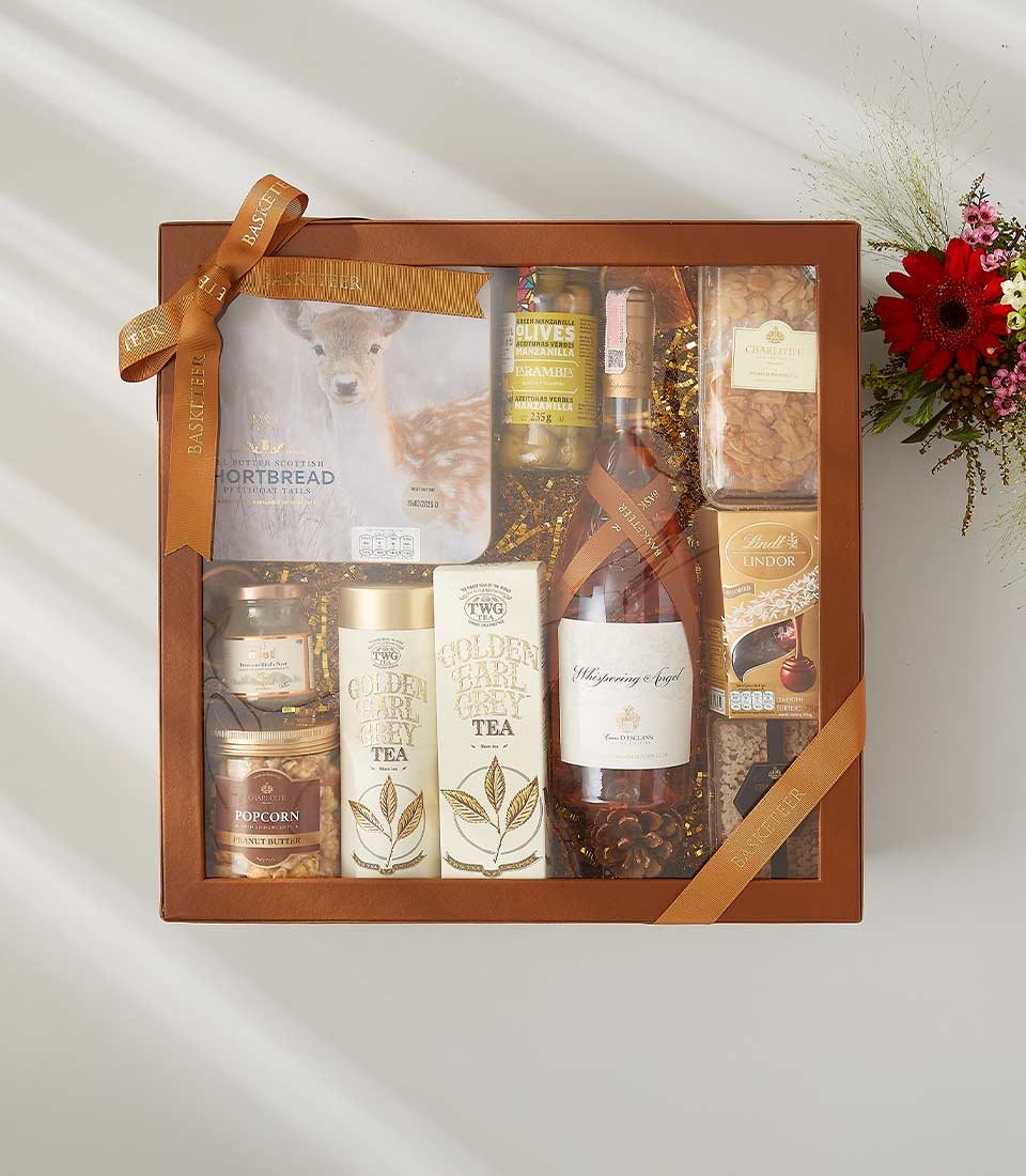 Luxury gift hamper with rosé wine, gourmet tea, Scottish shortbread, olives, popcorn, chocolates, and assorted treats With a lid and beautifully tied with a bow.