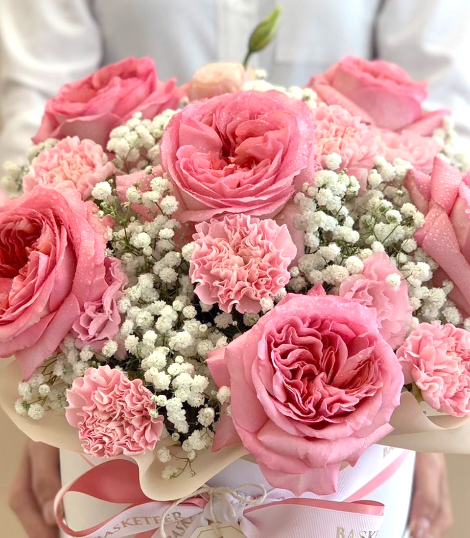 Elegant arrangement of pink roses, carnations, and baby’s breath in a white gift box with pink ribbons and a congratulatory card.
