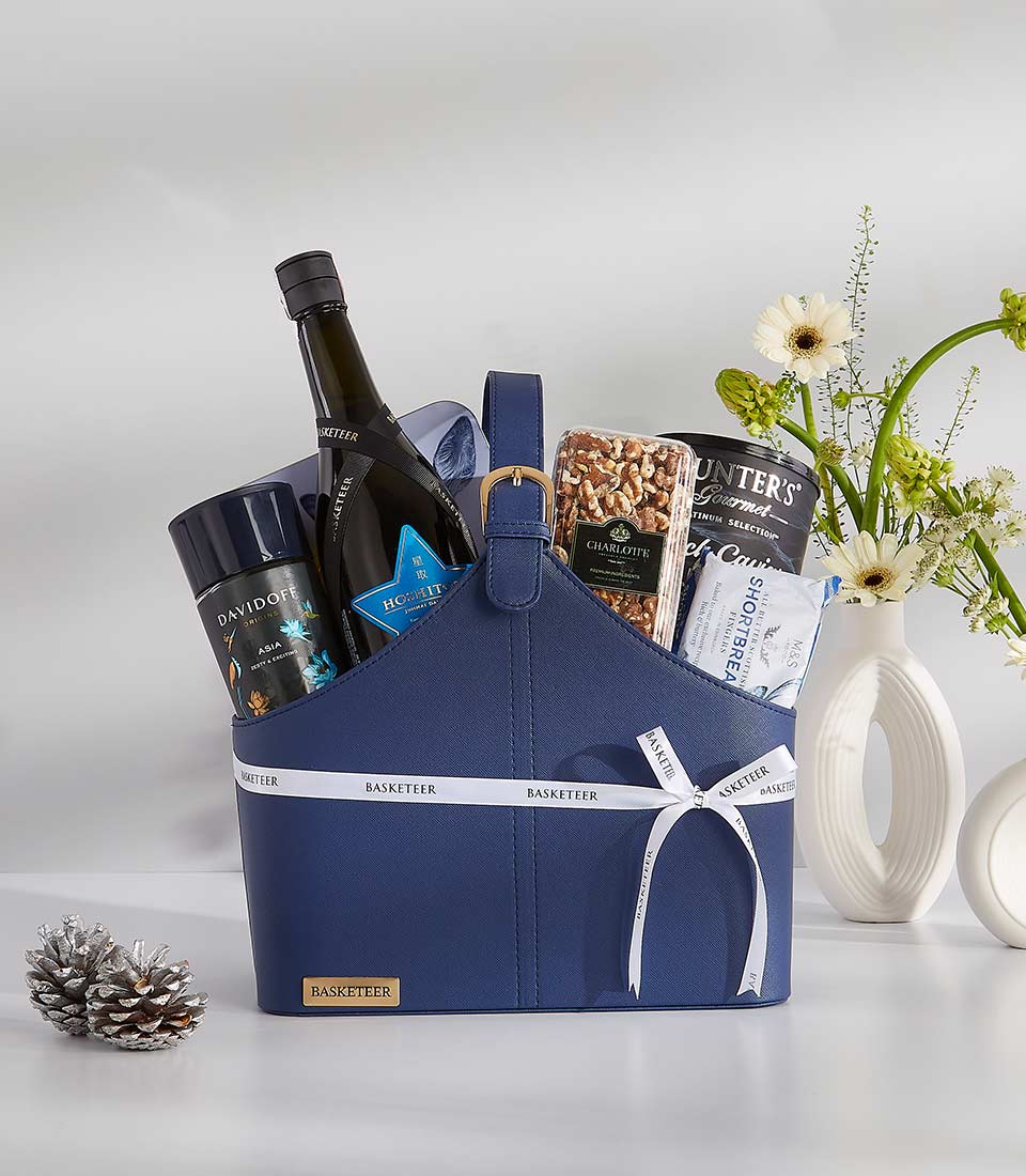 A navy blue gift basket filled with a variety of gourmet treats and a bottle of sparkling wine.
