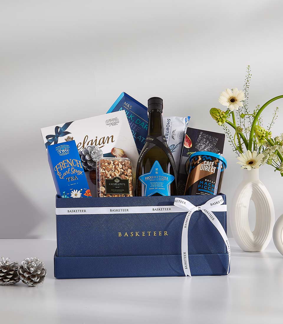 A navy blue gift basket filled with a variety of gourmet treats and a bottle of sparkling wine.