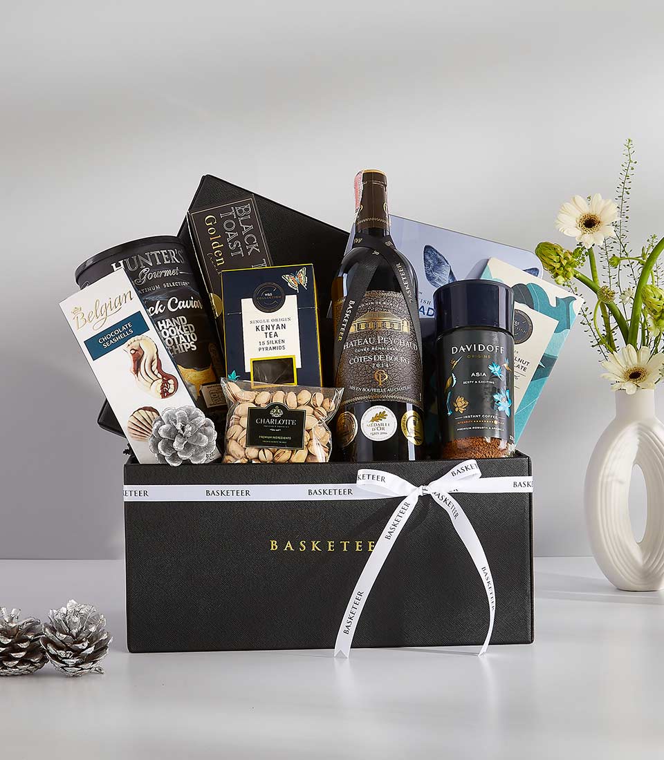 A navy black gift basket filled with a variety of gourmet treats and a bottle of sparkling wine.