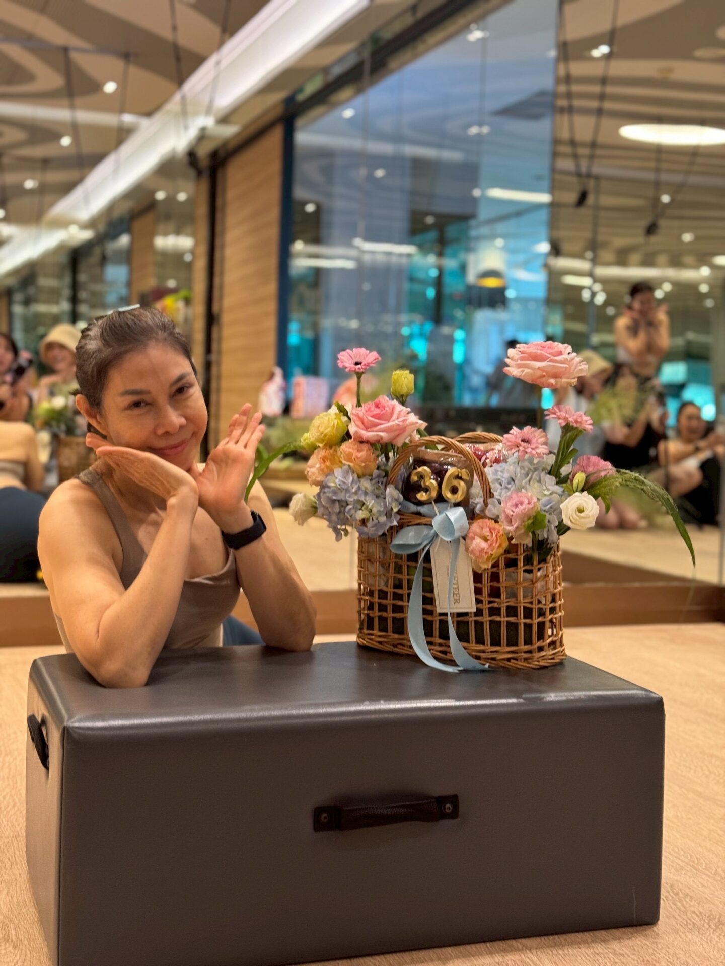 A radiant woman poses gracefully beside a luxurious flower-adorned fruit basket and 