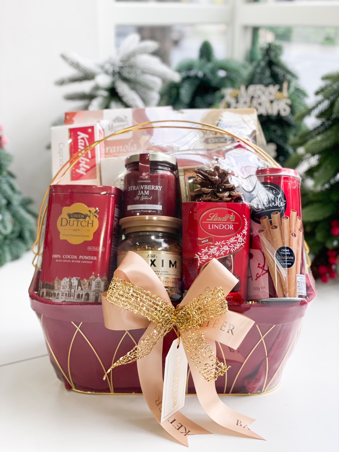 Premium gift hamper with assorted cookies, chocolates, coffee, strawberry jam, and a gold decorative ribbon.