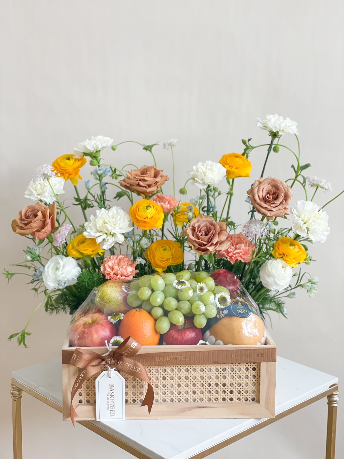 Vibrant Elegance Fruit Basket with fresh apples, oranges, grapes, and colorful flowers.