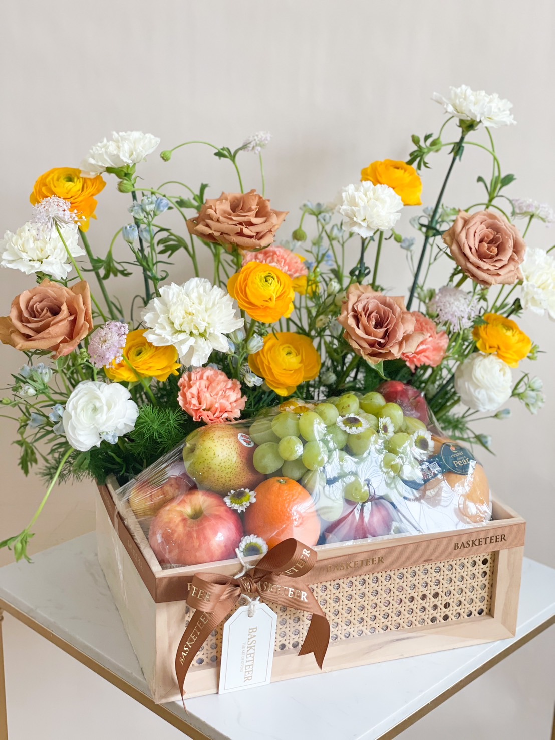 Vibrant Elegance Fruit Basket with fresh apples, oranges, grapes, and colorful flowers.