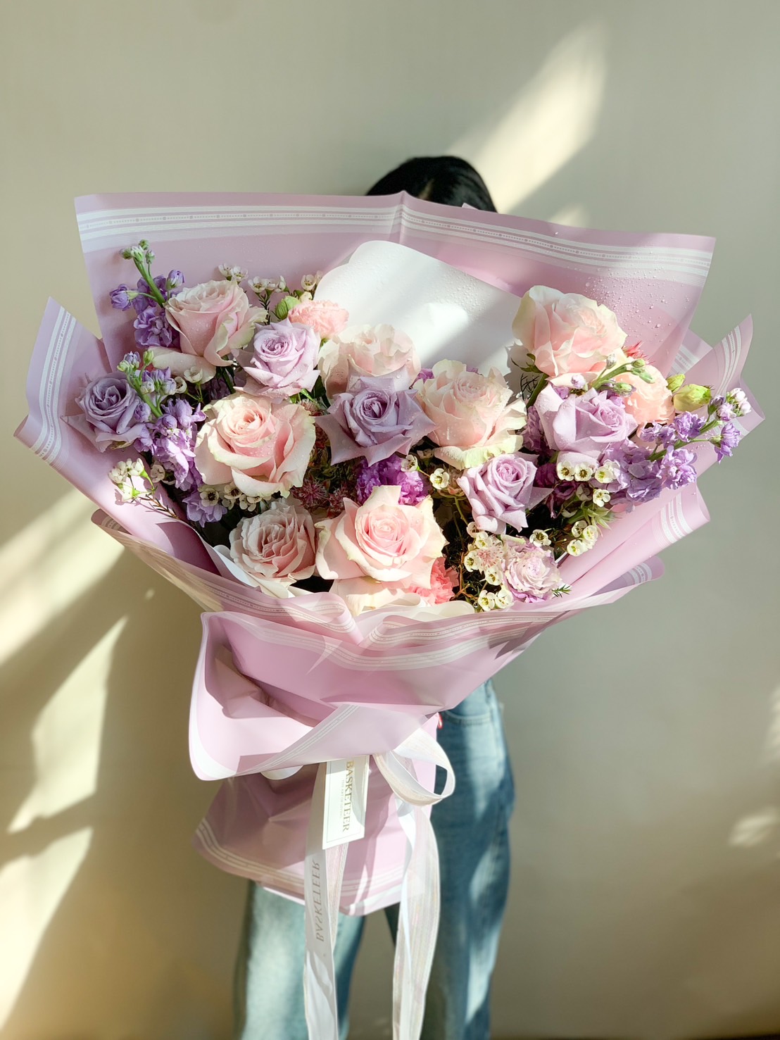 A beautiful bouquet of pink and lavender roses, elegantly wrapped in soft pink paper, perfect for romantic and special occasions.
