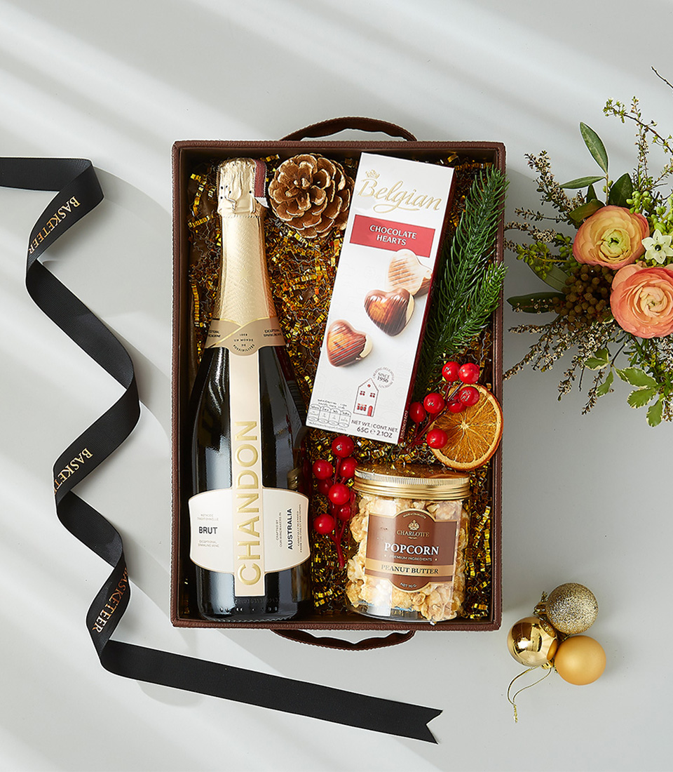 A brown leather tray filled with a bottle of Chandon Brut sparkling wine, a box of Belgian chocolate hearts