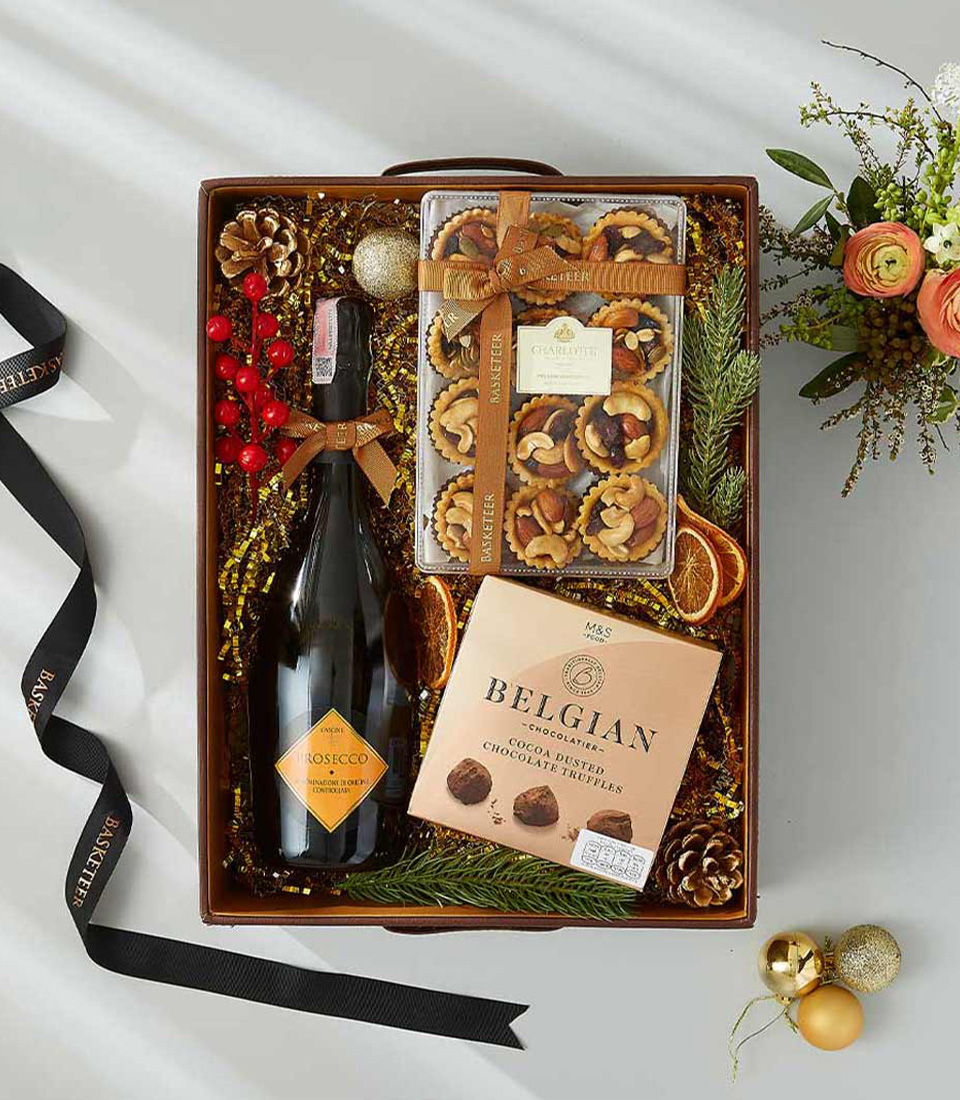 A Christmas gift box with a bottle of Prosecco, chocolates, and cookies.