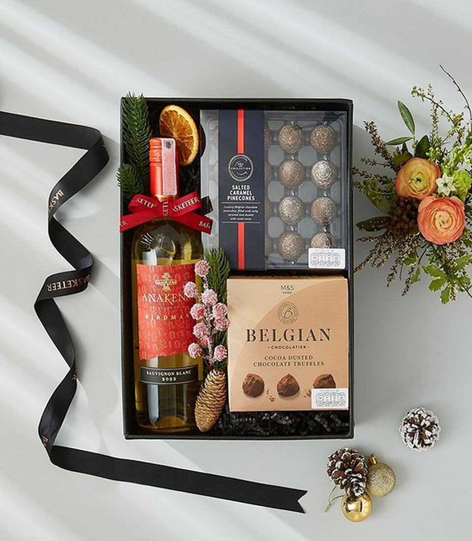 A gift box containing a bottle of Sauvignon Blanc wine, a box of salted caramel pine cones, and a box of cocoa dusted chocolate truffles.