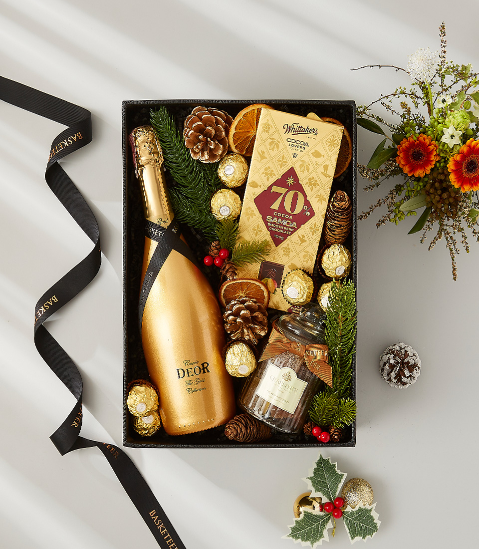 A luxurious holiday gift box filled with a golden bottle of champagne, a selection of fine chocolates