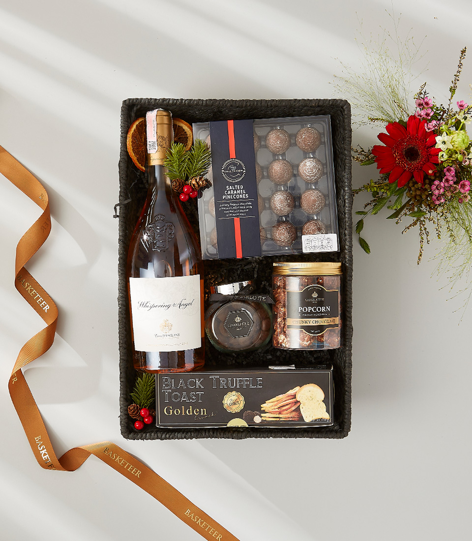Whispering Angel Rosé and gourmet gift basket with chocolates, truffle toast, and popcorn.